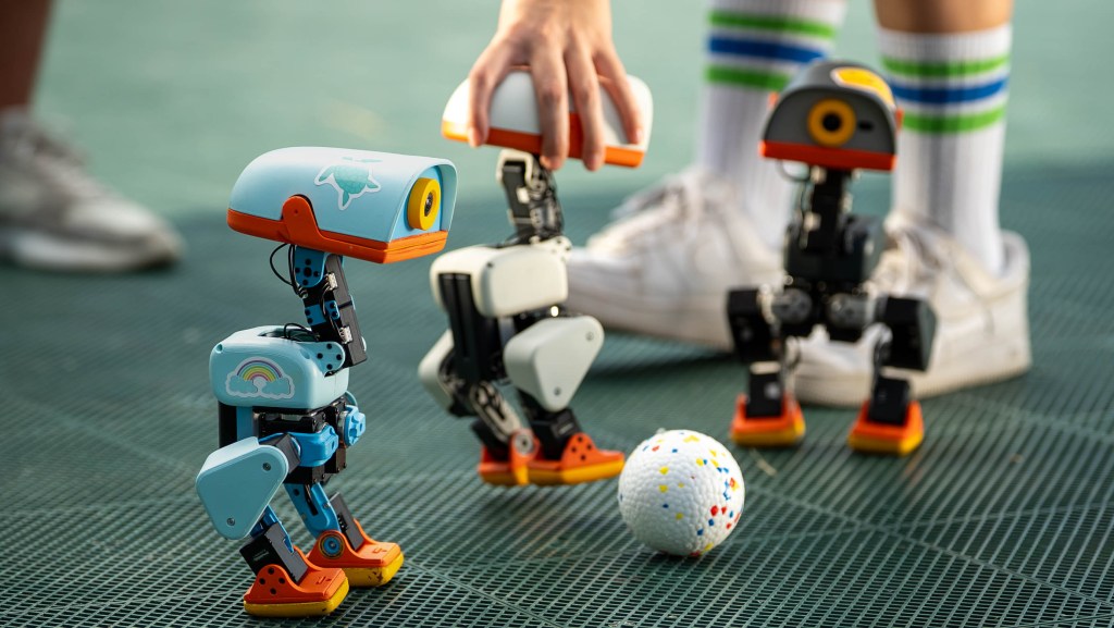 Small Microduck robots playing with a ball