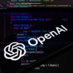 OpenAI logo on a phone with code in the background