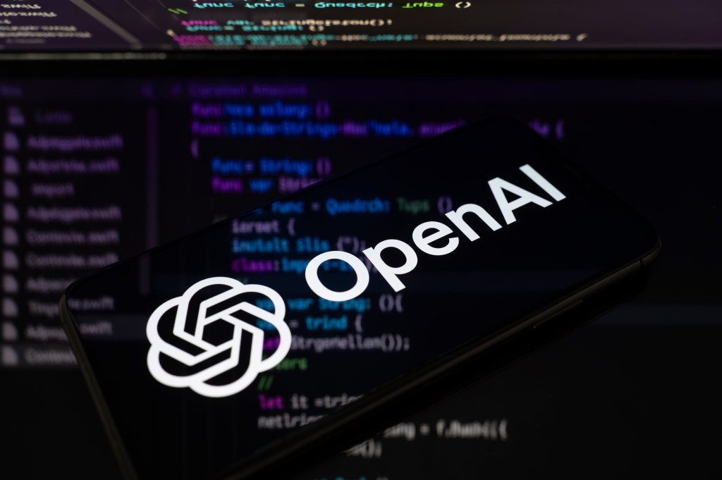 OpenAI logo on a phone with code in the background